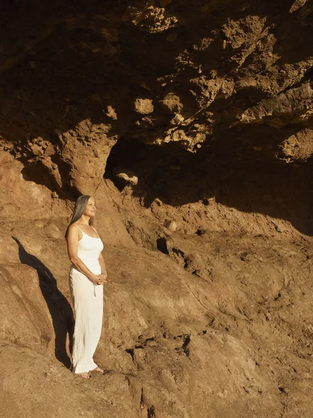 Senior Hispanic woman standing on rock formation
