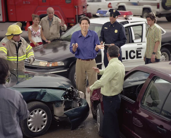 Hispanic man shrugging shoulders in middle of accident scene
