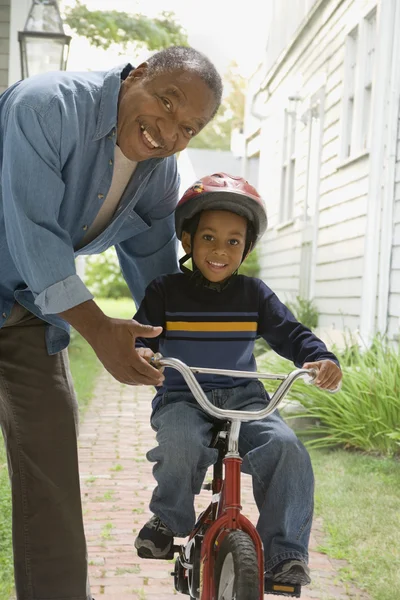 African grandfather teaching grandson to ride bicycle