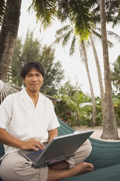 Asian man with laptop in hammock