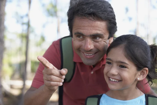 Hispanic father pointing for daughter in woods