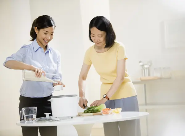 Asian mother and adult daughter preparing food