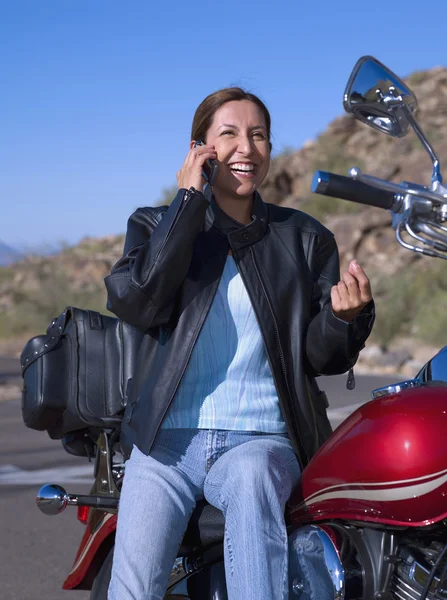 Woman on motorcycle talking on cell phone