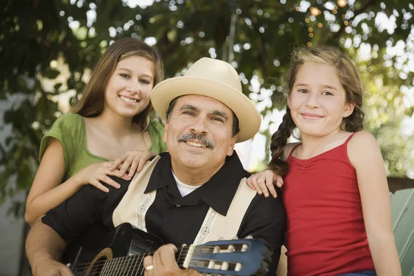 Hispanic father playing guitar for daughters