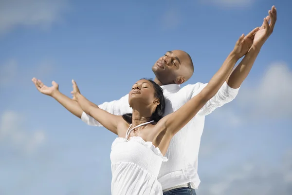 Multi-ethnic couple with arms raised