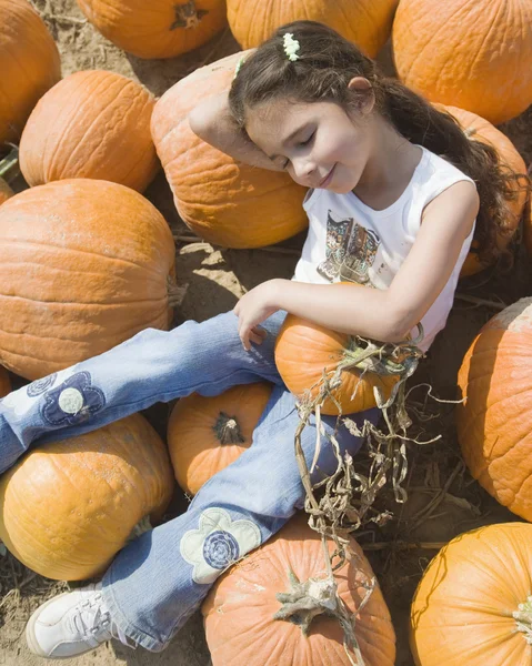 Hispanic girl laying in pumpkin patch