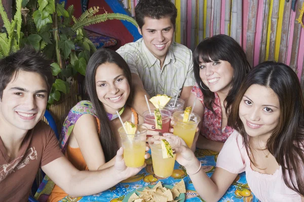 Young Hispanic friends toasting with cocktails