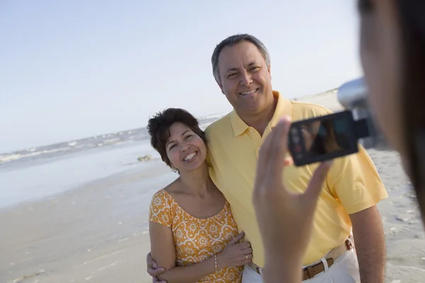 Hispanic couple being video recorded at beach