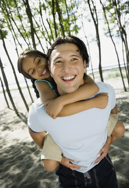 Mixed Race father giving daughter piggyback ride