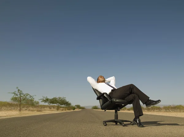 African businessman sitting in middle of road