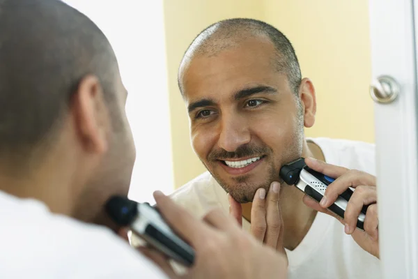 Middle Eastern man shaving with electric razor