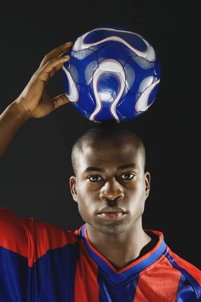 African American man holding soccer ball on head