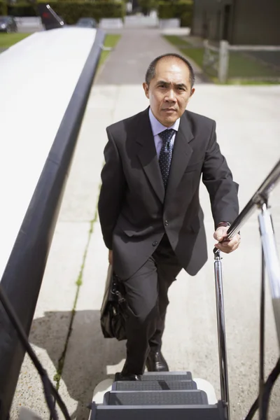 Asian businessman walking up airplane steps