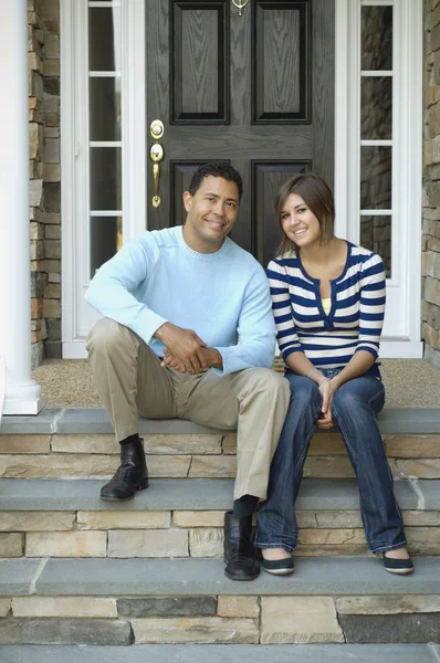 Hispanic father and daughter sitting on porch steps
