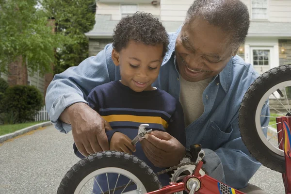 African grandfather and grandson fixing bicycle