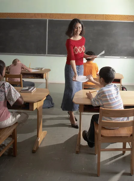 Indian female teacher handing back papers