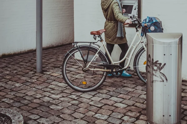 Girl with vintage city bicycle near ATM in Copenhagen