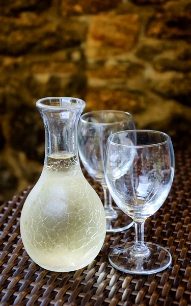 Ornate pitcher with cold white wine and two empty glasses