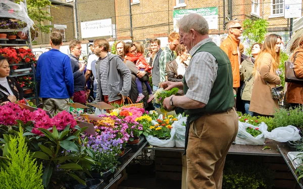 Senior vendor sells flowers at Columbia Road Flower Market.