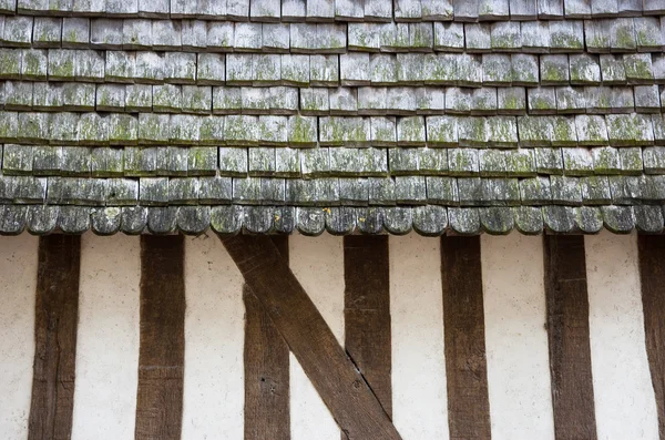 Old half timbered house house wall with traditional wooden tiled roof.