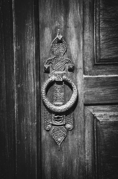 Castle gate doorknocker. Aged photo. Vignette. Black and white.