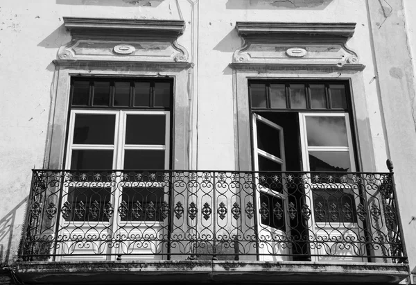 Balcony with wrought iron railing. Old typical house in Evora, Portugal. Historic Centre of Evora is a UNESCO World Heritage Site. Aged photo. Black and white.