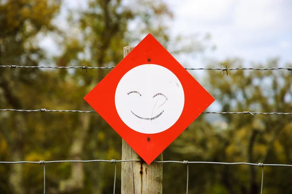 Stop sign with smile attached to barbed wire fence. Never stop smiling / Be positive concepts.