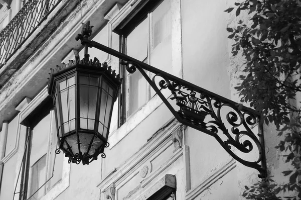 Lantern with Lisbon symbol (ship with two ravens) on the old building in the centre of Lisbon (Portugal). Aged photo. Black and white.