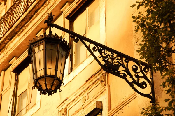 Lantern with Lisbon symbol (ship with two ravens) on the old building in the centre of Lisbon (Portugal). Golden sunset light. Toned photo.