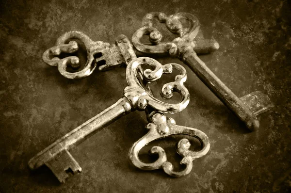 Four vintage keys. Retro aged toned photo with scratches. Sepia.