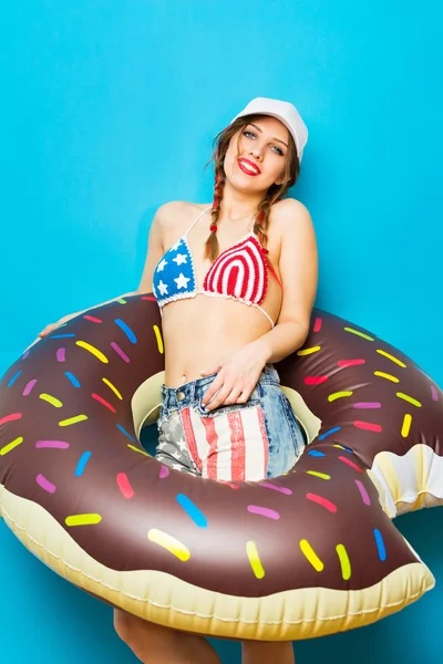 Cool teenage girl in bikini with inflatable donut float