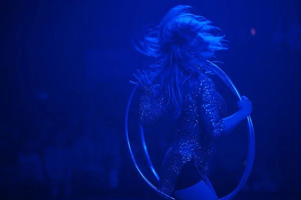 Circus performance concept. Dancing woman rotates hula hoop