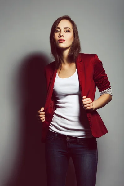 Casual street style fashion concept. Beautiful young fit woman in red jacket