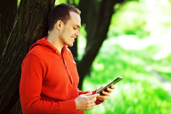 Gadget user concept. Portrait of happy young guy in orange sweat