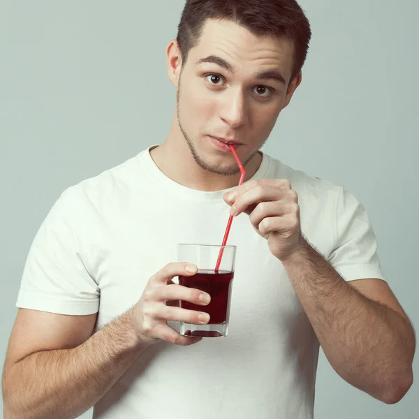 Portrait of happy funny young muscled man drinking grape, pomegranate juice
