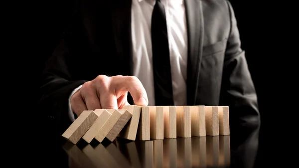 Businessman Stopping the Domino Effect