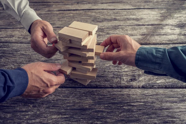 Three Businessmen Playing Wooden Tower Game