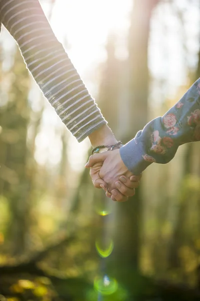 Closeup of two women holding hands outside in a beautiful forest