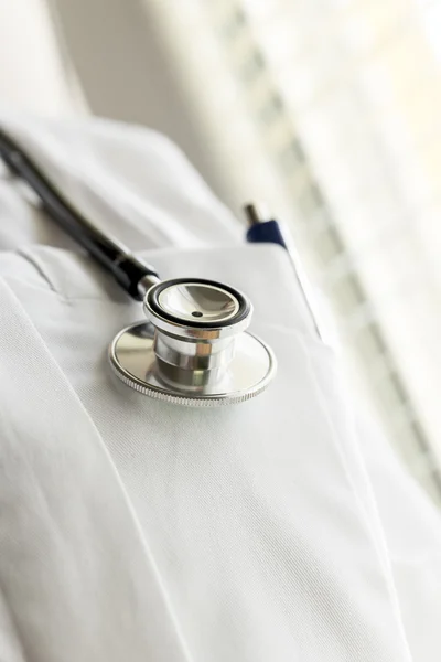 Closeup of disc of a stethoscope hanging over doctor robe