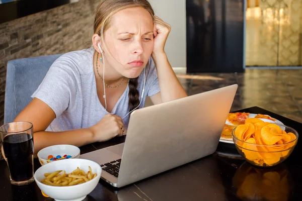 Woman works at the computer and eating fast food. Unhealthy Life