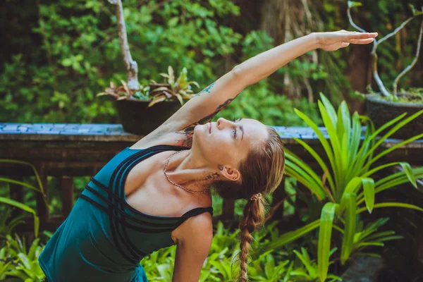 Pretty young woman doing yoga outside in natural environment