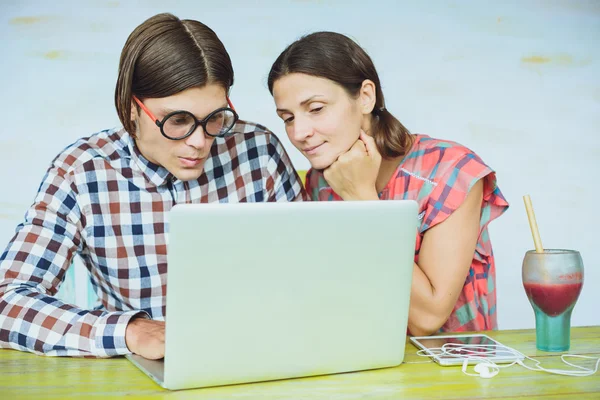 Surprised young nerd couple in glasses looking at computer monit