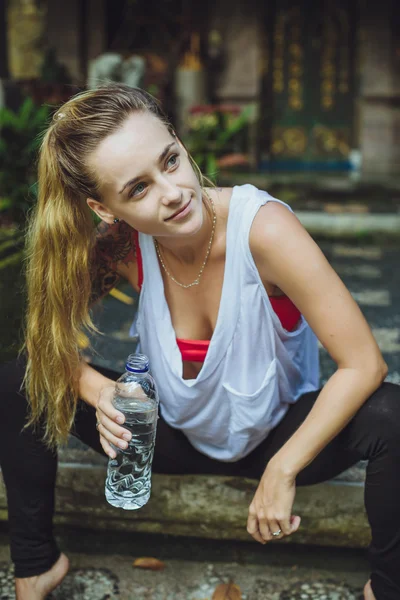 Portrait of young woman drinking water. Stylish Girl against nat