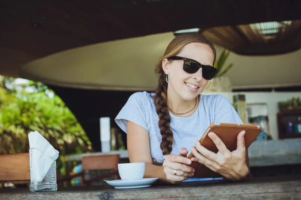 Young woman drinking coffee and watching at tablet at restaurant