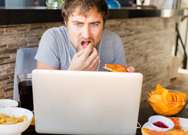 Man working at the computer and eating fast food. Unhealthy Life