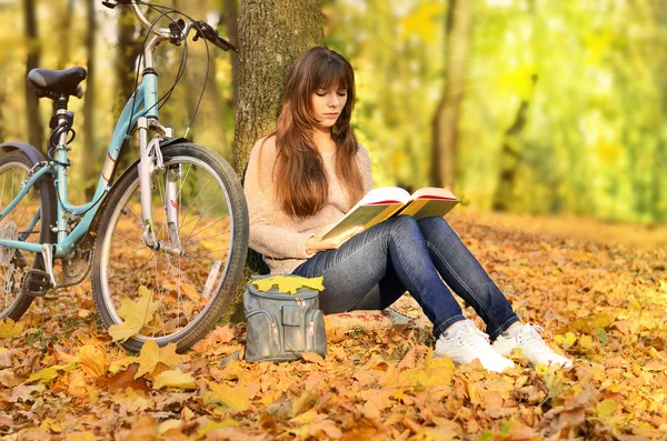 Girl reading a book in the park and bike