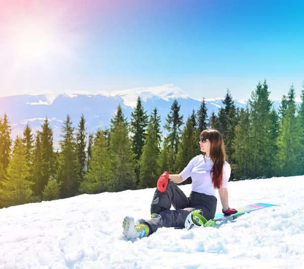Young snowboarder resting on the mountainside