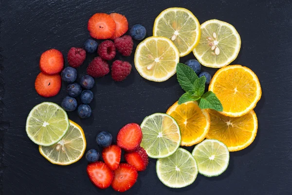 Assortment of citrus and fresh berries on a dark background
