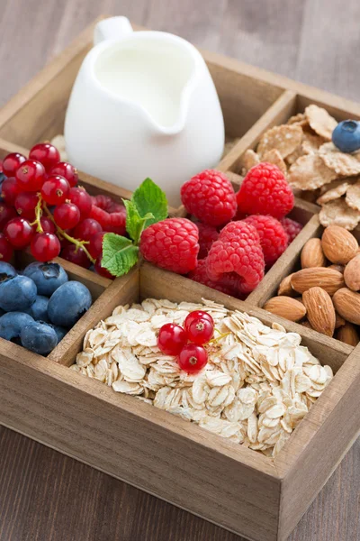 Wooden box with breakfast items - oatmeal, granola, nuts, berry
