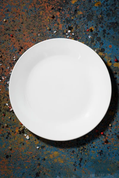 Empty white plate on a dark background, vertical, top view